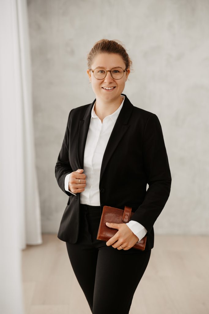 Zeigt eine junge Frau mit einer Mappe in der Hand nach einem Seminar im Bereich strategisches Marketing